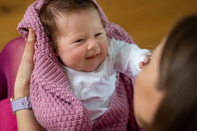 doula trzyma uśmiechnięte niemowlę